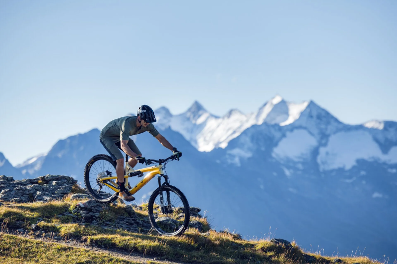 Mountainbiker op een bergtop met besneeuwde toppen op de achtergrond